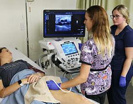 Female student standing next to ultrasound machine